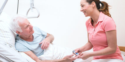 Pflegerin bei der Blutzuckermessung beim Patienten